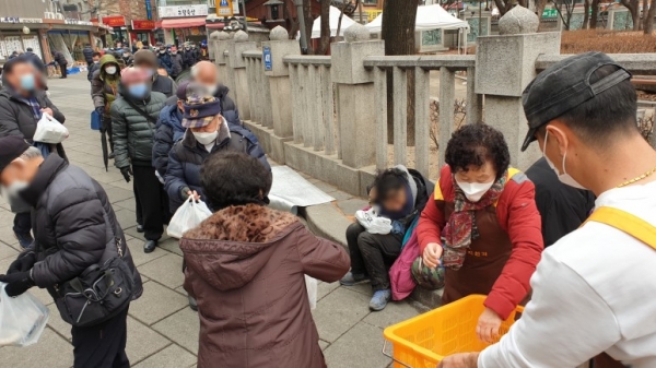 탑골공원 북문에서 도시락을 나눠 주는 원각사 무료급식소 후원자와 자원봉사자들(불교닷컴 자료사진)